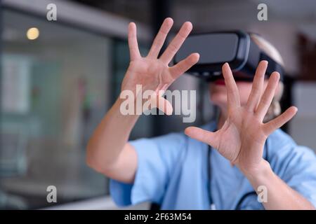 Kaukasische Ärztin trägt Peelings mit vr-Headset und virtuelle Schnittstelle Stockfoto