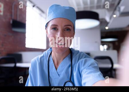 Kaukasische Ärztin mit Peelings, die während des Gesprächs am Schreibtisch sitzt Videokonferenz Stockfoto