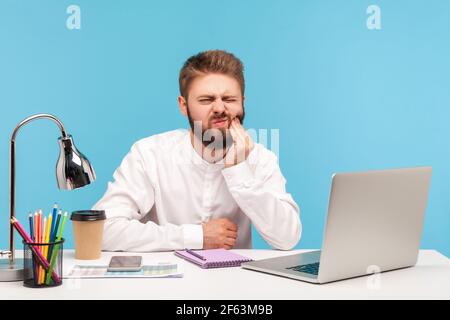 Unglücklicher bärtiger Mann Büroangestellter Berührung Wange mit Fingern Gefühl unangenehme Zahnschmerzen, leiden Zahnfleisch Entzündung, Zahnheilkunde Probleme. Innenst Stockfoto