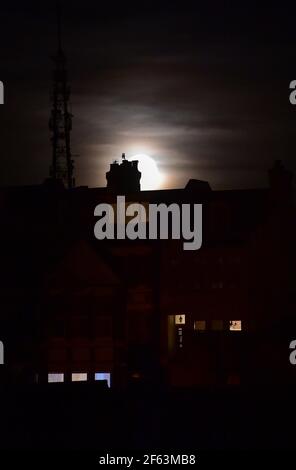 Brighton UK 29th March 2021 - der Worm Moon erhebt sich heute Abend über Häusern im Queens Park von Brighton. Dies wird der erste Supermond des Jahres sein, was bedeutet, dass der Mond etwas näher an der Erde ist und daher am Himmel größer und heller erscheint. : Credit Simon Dack / Alamy Live News Stockfoto