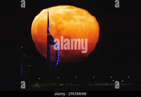 Portsmouth, Hampshire. 29th. März 2021. Wetter in Großbritannien. Der Super Worm Moon steigt an einem klaren Abend an der Südküste hinter dem Spinnaker Tower in Portsmouth auf. Der Supermond scheint den 560 Meter hohen Turm in den Schatten zu stellen, als er sich vom Horizont erhebt. Credit Stuart Martin/Alamy Live News Stockfoto