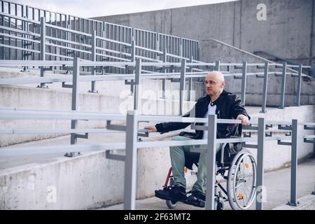 Behinderter Mann im Rollstuhl am Anfang der Rampe. Stockfoto