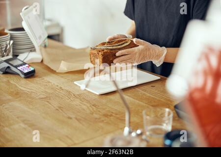 Weibliche Barista an der Vitrine mit Desserts im Café. Junger Arbeiter des Süßes und des Cafés Stockfoto
