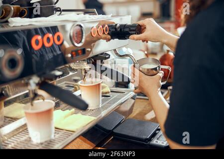 Bild einer Barista, die die Milch mit einer Kaffeemaschine aufschäumt Im Café Stockfoto
