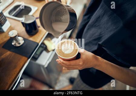 Barista bereitet Cappuccino zu, Barkeeper bereitet Kaffeegetränk zu. Kaffeetasse mit Latte Art Stockfoto