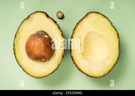 Avocado Hass in zwei Hälften geschnitten. Draufsicht. Gesunde Ernährung. Obst auf grünem Hintergrund. Stockfoto
