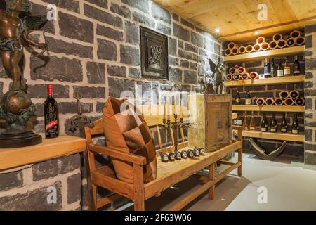 Lange Sitzbank aus Holz mit mittelalterlichen Gegenständen im Weinkeller Mit imitierten Steinmauern in einer alten, ca. 1790 kanadischen Stadt Haus im Cottage-Stil Stockfoto