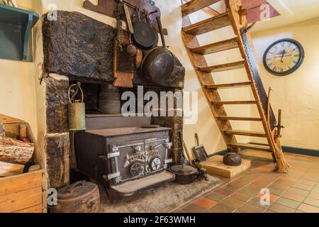 Marksman Gusseisen Holzofen in Granit Kamin im Abendessen Zimmer mit Kiefernholz Miller's Treppe und grau und Terrakotta Fliesenboden aus Keramik Stockfoto