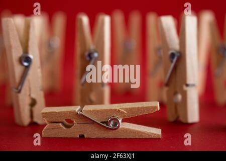 Darstellung von Menschen mit Wäscheklammern. Konzept der Krankheit oder Tod und letzte Auf Wiedersehen. Selektiver Fokus auf rotem Hintergrund. Stockfoto