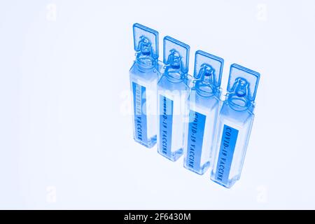 Blaue Fläschchen mit Covid-19-Impfstoff auf weißem, durchscheinendem Hintergrund Stockfoto