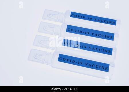 Blaue Fläschchen mit Covid-19-Impfstoff auf weißem, durchscheinendem Hintergrund Stockfoto