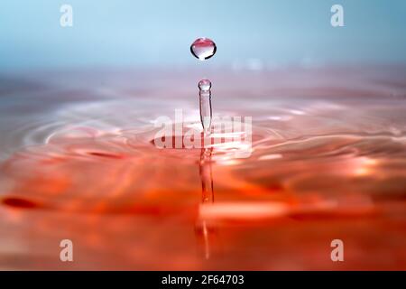 Moment der Kollision von Wassertropfen auf rosa Hintergrund. Abstrakter natürlicher Hintergrund Stockfoto