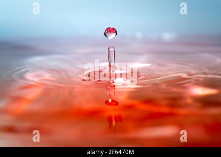 Moment der Kollision von Wassertropfen auf rosa Hintergrund. Abstrakter natürlicher Hintergrund Stockfoto