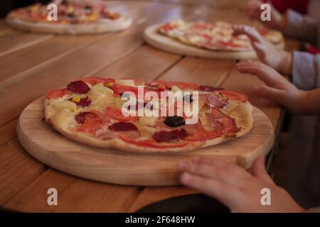 Womans Hand halten Pizza auf einem Holzbrett bestreut Mit Mehl Stockfoto