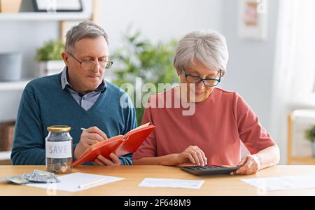 Ältere Ehepaare sitzen am Schreibtisch mit einem Papierbeleg in den Händen berechnen Kosten, Verwaltung der Familie Budget. Stockfoto