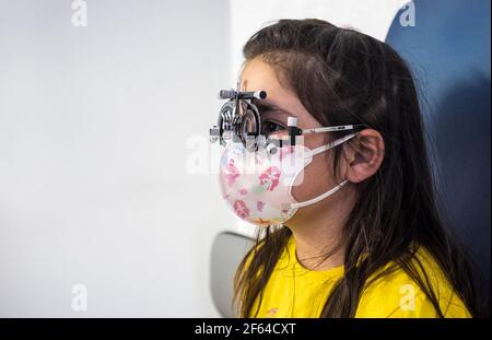 Kleines Mädchen tun Augentest bei Optiker. Kinder kümmern sich um Auge Konzept Stockfoto