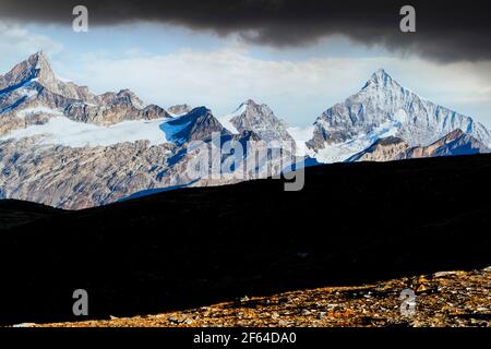 Wanderer mit Rucksack Wandern auf Bergrücken mit Weisshorn im Hintergrund, Kanton Wallis, Schweiz Stockfoto