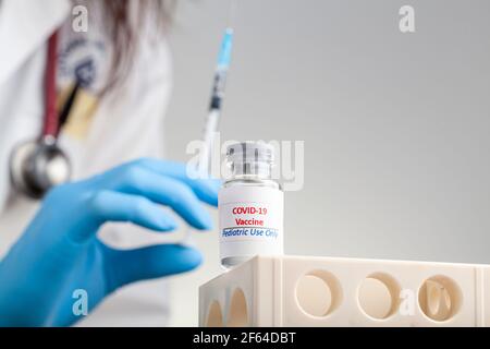 Konzeptbild mit COVID 19-Impfstoff, der nur für die pädiatrische Verwendung in einem Glasfläschchen mit einer gefüllten Nadel und Spritze vor der Verabreichung des Schusses entwickelt wurde. Stockfoto