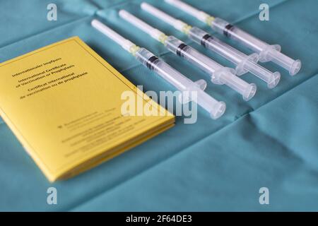 Impfstoffkonzept mit einer Reihe von Spritzen und gelb international Impfzertifikat auf einem grünen Operationsgewebe Stockfoto