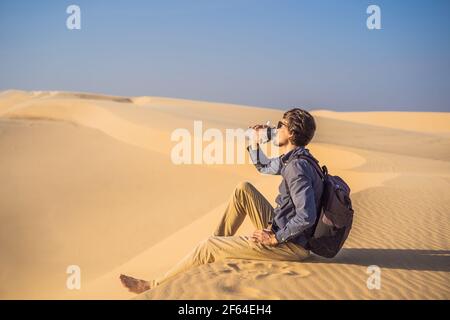 Der Mensch spürt Durst und trinkt Wasser in der Wüste Stockfoto