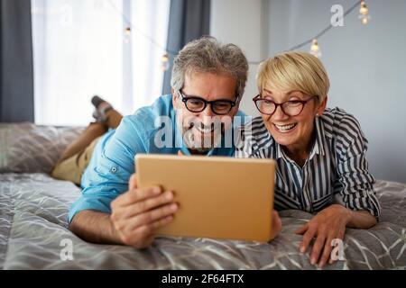 Schöne glücklich reifen Paar ist mit einem digitalen Tablet, reden und lächeln zu Hause Stockfoto