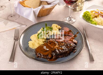 Schweinesteak mit Kartoffelpüree auf dem Restauranttisch Stockfoto