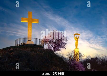 Christliches Kreuz mit blühendem Baum und Freiheitsstatue auf dem Hintergrund in Gellert Hill Budapest Ungarn Stockfoto