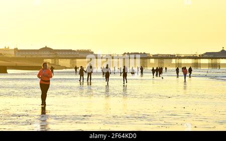 Brighton UK 30th März 2021 - früh am Morgen Wanderer , Paddelboarder und Schwimmer machen das Beste aus der extra Ebbe in Brighton an einem schönen sonnigen Morgen entlang der Südküste an dem, was prognostiziert wird, dass der wärmste Tag des Jahres bisher mit Temperaturen voraussichtlich Mitte 20s in einigen Teilen der sein UK : Credit Simon Dack / Alamy Live News Stockfoto