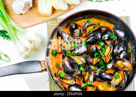 Köstliche Meeresfrüchte Muscheln mit roter Sauce und grünen Zwiebeln in Eine Pfanne Stockfoto