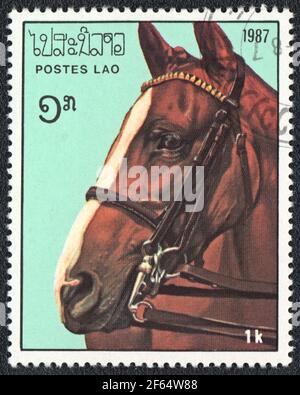 Eine in Laos gedruckte Briefmarke zeigt ein braunes mit weißem Pferd (Equus ferus caballus) aus der Serie: Vollblutpferde, um 1987 Stockfoto