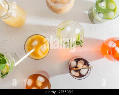 Verschiedene erfrischende alkoholfreie Getränke in Gläsern mit Eis. Verschiedene Säfte, hausgemachte Limonade, Eiskaffee, Eistee und Smoothies auf White BA Stockfoto
