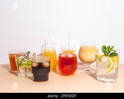 Verschiedene erfrischende alkoholfreie Getränke in Gläsern mit Eis. Verschiedene Säfte, hausgemachte Limonade, Eiskaffee, Eistee und Smoothies auf beige BA Stockfoto