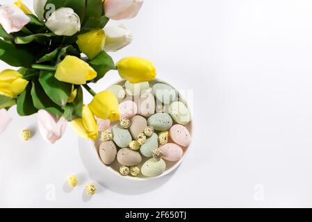 Ein Strauß Tulpen, Ostereier auf einem Teller auf weißem Hintergrund. Schöne Ostern Grußkarte. Stockfoto
