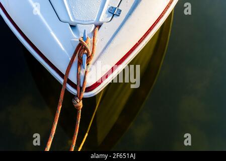 Weiße Yacht im Hafen festgemacht, Bug und Seile aus der Nähe. Morgen Ansicht von oben auf Segelboot Bug Stockfoto