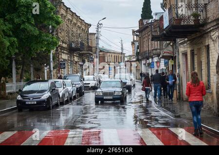 Kutaisi Street an einem regnerischen Tag mit geparkten Autos und Fußgängern. Georgien Stockfoto