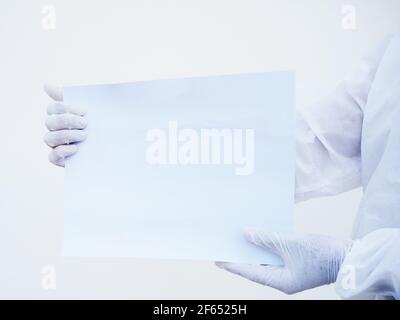 Nahaufnahme Hände des Arztes oder Wissenschaftlers in PSA-Uniform, die leeres Papier für Text mit beiden Händen halten, während sie nach vorne schauen. Coronavirus oder COVID-19 CO Stockfoto