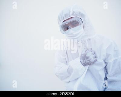 Asiatischer Arzt oder Wissenschaftler in PSA-Uniform mit Gesichtsmaske schützend tragen. Die Stimmung ist wie traurig und ruhig, Coronavirus oder COVID-19 Konzept Stockfoto