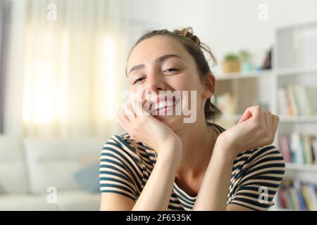 Ehrliche Frau lächelt der Kamera im Wohnzimmer zu Zu Hause Stockfoto