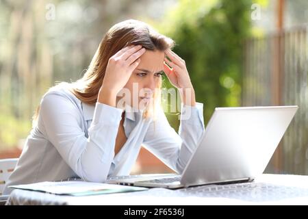 Besorgt Freelancer Überprüfung schlechte Nachrichten auf Laptop arbeiten in einem Hausterrasse Stockfoto