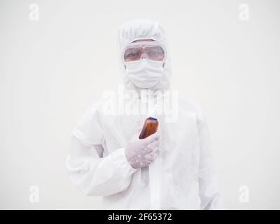 Porträt von Arzt oder Wissenschaftler in PSA-Suite Uniform halten Plastikflasche mit Hautpflegeprodukt. COVID-19 Concept isolierter weißer Hintergrund Stockfoto