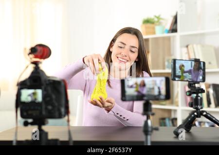 Glücklicher Influencer, der Videos mit kinetischem Sand mit mehreren Aufnahmen aufzeichnet devices.jpg Stockfoto