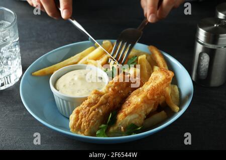 Weibliche Hände halten Besteck über den frittierten Fisch und Chips, Nahaufnahme Stockfoto