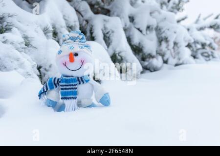 Spielzeug fröhlich Schneemann im Winterwald auf dem Hintergrund Von schneebedeckten Bäumen Stockfoto