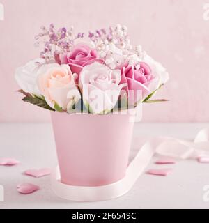 Festliche Komposition mit schönen zarten Rosen Blumen in rosa runde Box auf hellrosa Hintergrund. Glückwunschkarte zum Muttertag. Quadratisches Bild. Stockfoto