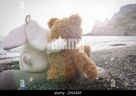 Ein Spielzeug Hase und ein Bär sitzen Blick auf die Meer Stockfoto