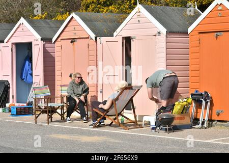 Bournemouth, Dorset, Großbritannien, 30.. März 2021, Wetter. Eine frühe Frühjahrshitzewelle. Leute mit Liegestühlen, die sich für den Tag außerhalb der Strandhütten an der Promenade einrichten. Stockfoto