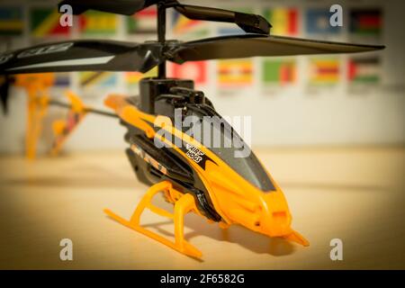 Avola, Sizilien - März 21st 2021: Nahaufnahme eines Air Hogs Helikopterspielzeugs über einem Holztisch. Das Spielzeug hat 2 Rotoren und ist schwarz und orange Farbe. Stockfoto