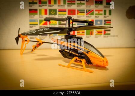 Avola, Sizilien - März 21st 2021: Nahaufnahme eines Air Hogs Helikopterspielzeugs über einem Holztisch. Das Spielzeug hat 2 Rotoren und ist schwarz und orange Farbe. Stockfoto