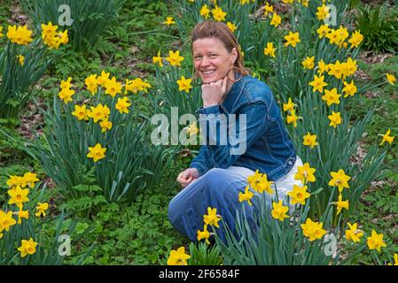 Edinburgh, Schottland, Vereinigtes Königreich Wetter. März 2021. Bewölkt im Wald, Temperatur 15 Grad Celsius. Anna Neubert-Wood of WanderWomen Scotland genießt die Ruhe und Einsamkeit inmitten der goldenen Narzissen. Anna teilt ihre Leidenschaft für die Natur gerne mit gleichgesinnten Frauen: An schönen Orten wandern, alles, was sie braucht, im Rucksack, wandern und Wunder in der Natur finden, eins sein mit dem, was sie und ihre Begleiter umgibt. Stockfoto