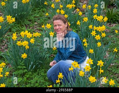 Edinburgh, Schottland, Vereinigtes Königreich Wetter. März 2021. Bewölkt im Wald, Temperatur 15 Grad Celsius. Anna Neubert-Wood of WanderWomen Scotland genießt die Ruhe und Einsamkeit inmitten der goldenen Narzissen. Anna teilt ihre Leidenschaft für die Natur gerne mit gleichgesinnten Frauen: An schönen Orten wandern, alles, was sie braucht, im Rucksack, wandern und Wunder in der Natur finden, eins sein mit dem, was sie und ihre Begleiter umgibt. Stockfoto